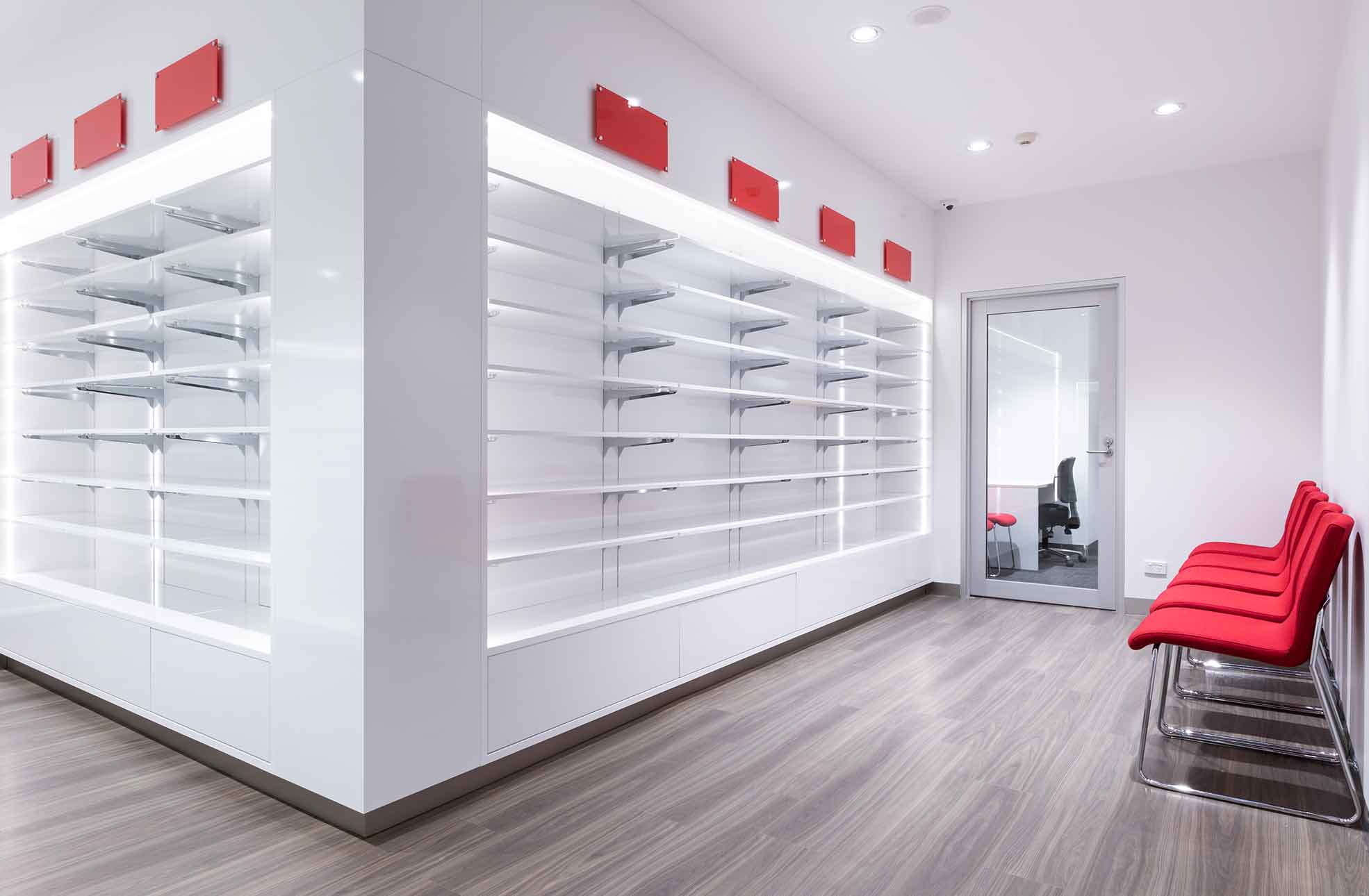 Retail fitout showing rows of white shelving for retial pharmacy