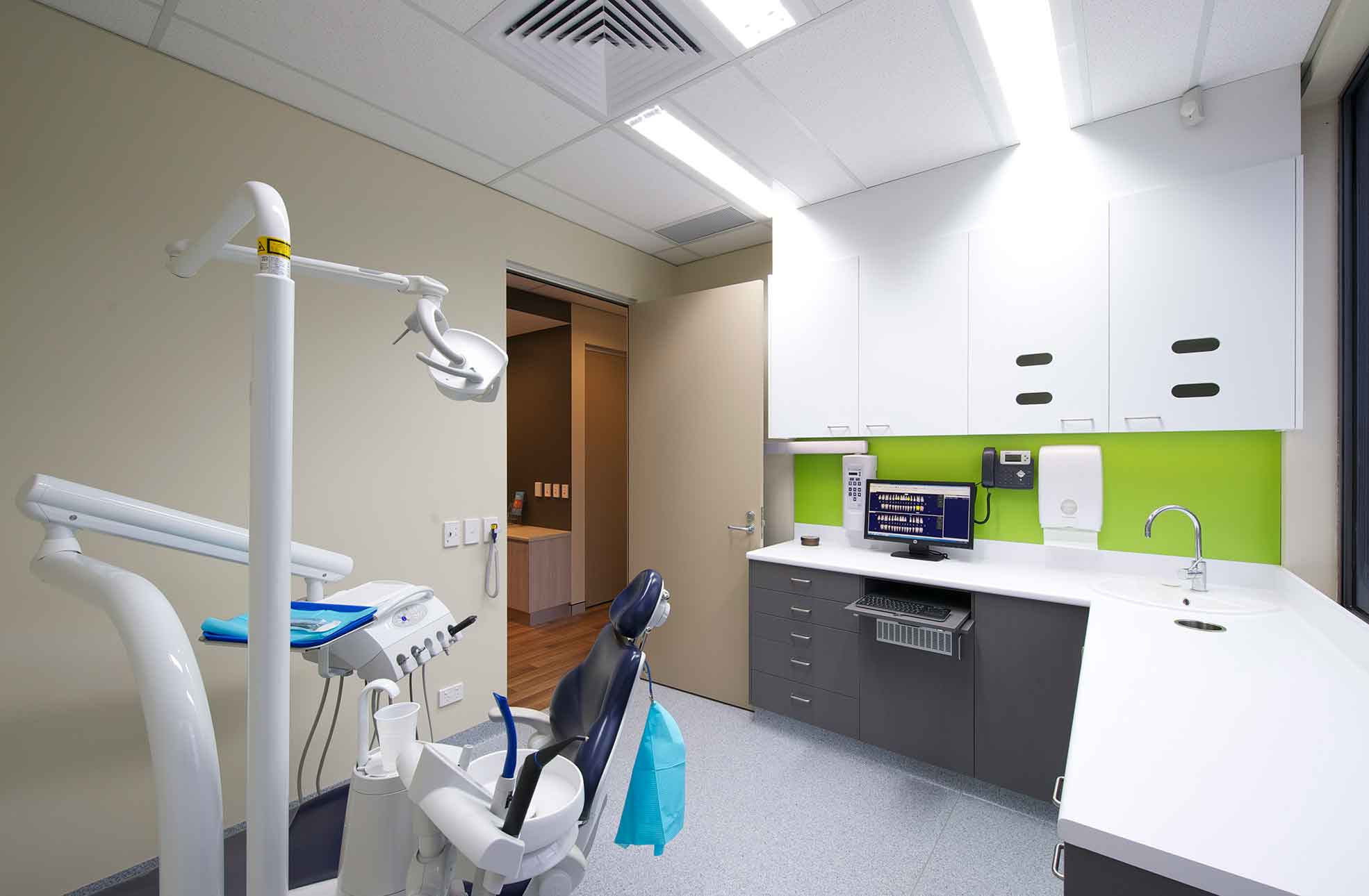 Dental clinic fitout showing patient chair, cupbaods, sink & clean layout.